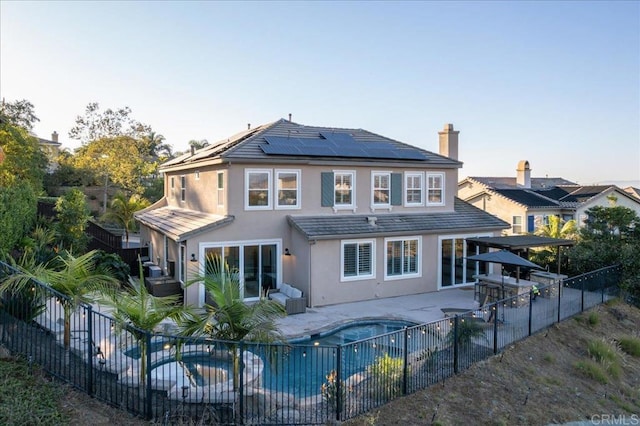 back of house with a pool with hot tub, solar panels, and a patio