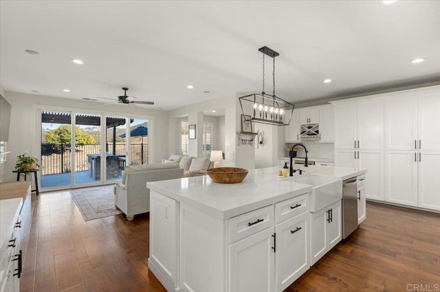 kitchen with ceiling fan, sink, white cabinets, and a center island with sink