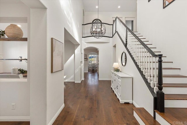 foyer entrance with an inviting chandelier, dark hardwood / wood-style flooring, and a high ceiling