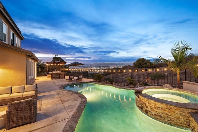 pool at dusk featuring an in ground hot tub and a patio