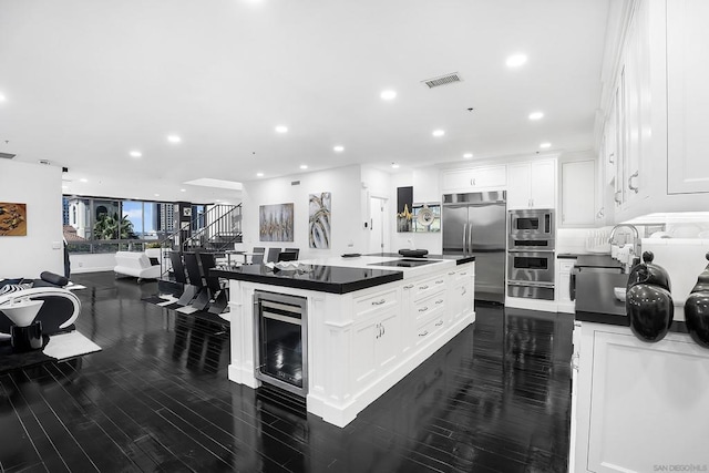 kitchen featuring wine cooler, built in appliances, white cabinetry, and a center island