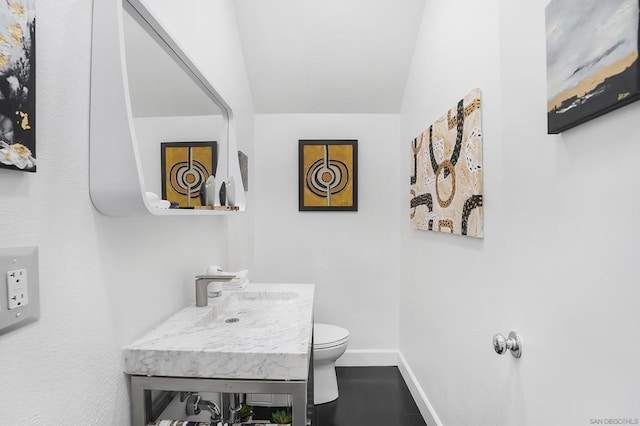 bathroom featuring toilet, vanity, and vaulted ceiling