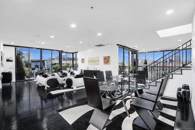 workout area with hardwood / wood-style floors, a wall of windows, and a skylight