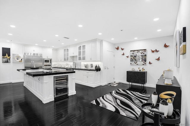 kitchen featuring a center island, wine cooler, built in appliances, white cabinets, and sink