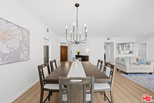 dining area featuring light wood-type flooring, crown molding, and a notable chandelier