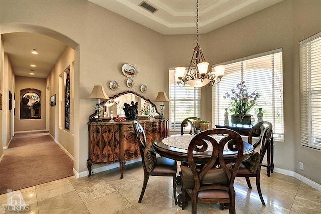 dining room with a chandelier, a healthy amount of sunlight, and a raised ceiling