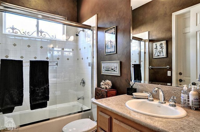 full bathroom featuring toilet, bath / shower combo with glass door, and vanity