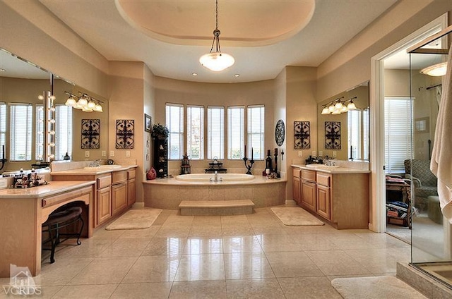 bathroom featuring tile patterned flooring, tiled tub, a raised ceiling, and vanity