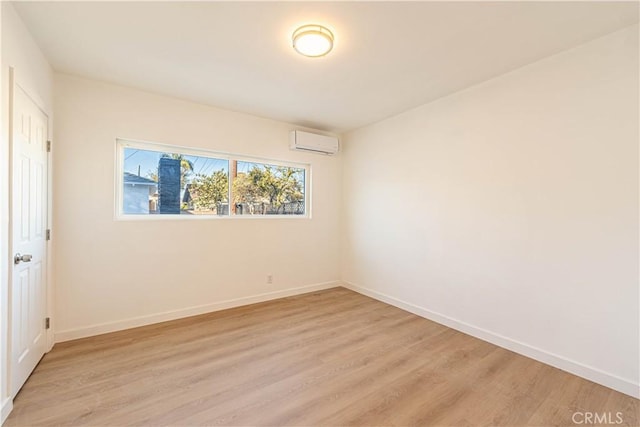 spare room with light hardwood / wood-style floors and an AC wall unit