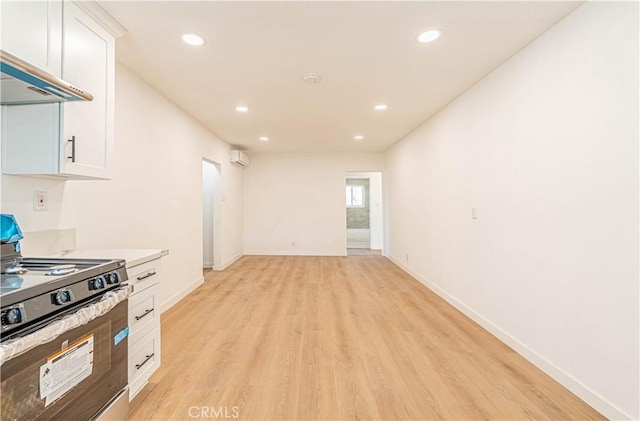 kitchen featuring white cabinetry, extractor fan, a wall mounted air conditioner, stove, and light hardwood / wood-style flooring