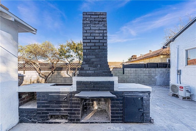 view of patio featuring exterior fireplace and ac unit