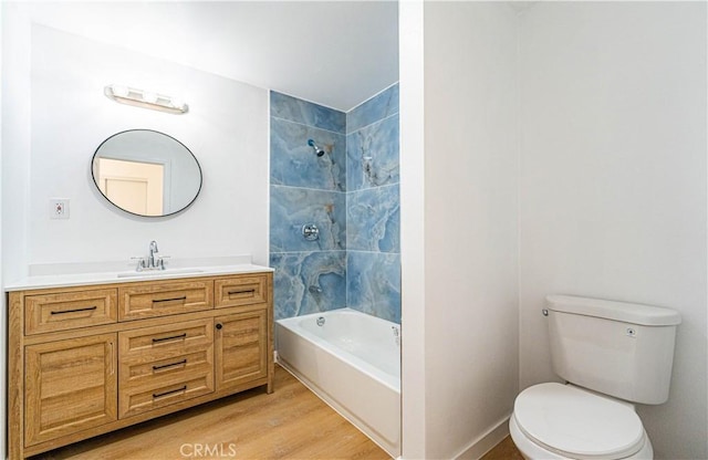 full bathroom with toilet, tiled shower / bath, vanity, and hardwood / wood-style flooring