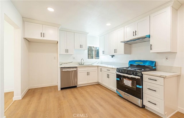 kitchen featuring light stone countertops, white cabinets, stainless steel appliances, sink, and light hardwood / wood-style flooring