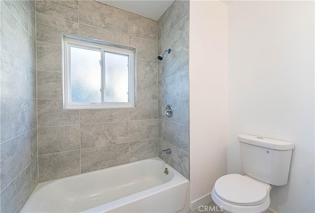 bathroom with tiled shower / bath combo and toilet