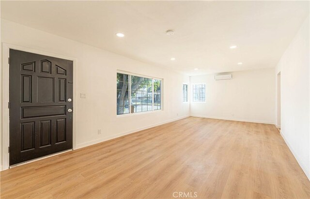 entrance foyer with a wall unit AC and light hardwood / wood-style flooring