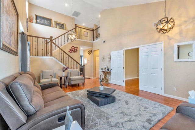 living room featuring an inviting chandelier, a towering ceiling, and light hardwood / wood-style flooring