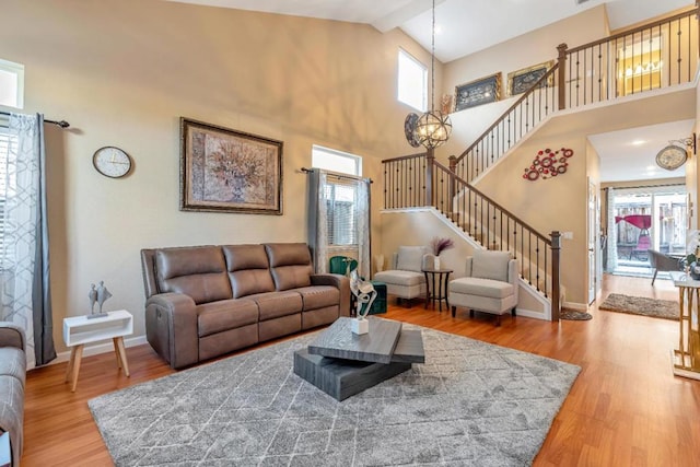 living room featuring hardwood / wood-style flooring, a notable chandelier, and high vaulted ceiling