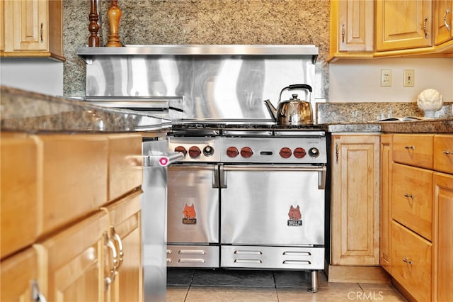 kitchen featuring dark stone countertops, dark tile patterned flooring, and range with two ovens