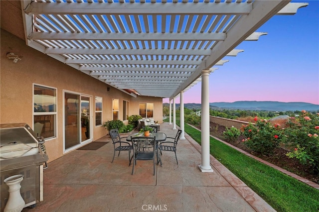 patio terrace at dusk with a pergola and area for grilling