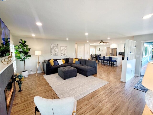 living room with ceiling fan and light wood-type flooring