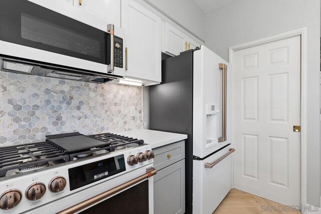 kitchen featuring light parquet flooring, white cabinets, white appliances, and decorative backsplash