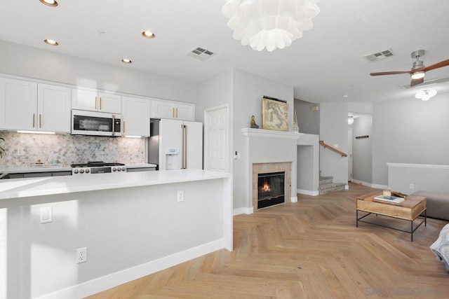 kitchen with white appliances, ceiling fan, light parquet flooring, decorative backsplash, and white cabinets