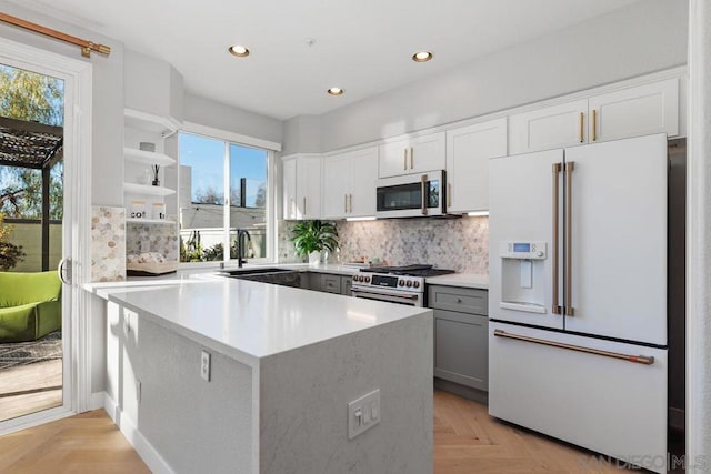 kitchen featuring sink, light parquet floors, white cabinetry, premium appliances, and decorative backsplash