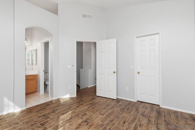 unfurnished bedroom featuring ensuite bath and light hardwood / wood-style flooring