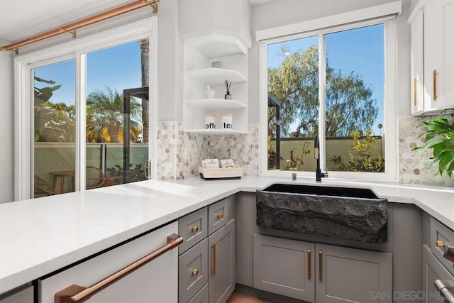 interior space with tasteful backsplash, sink, gray cabinets, and dishwasher