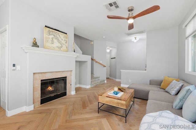 living room with a tiled fireplace, parquet floors, and ceiling fan