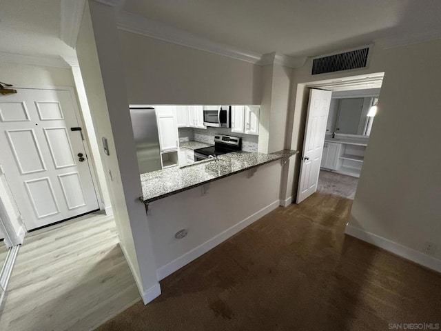 kitchen featuring light stone countertops, white cabinetry, stainless steel appliances, tasteful backsplash, and kitchen peninsula