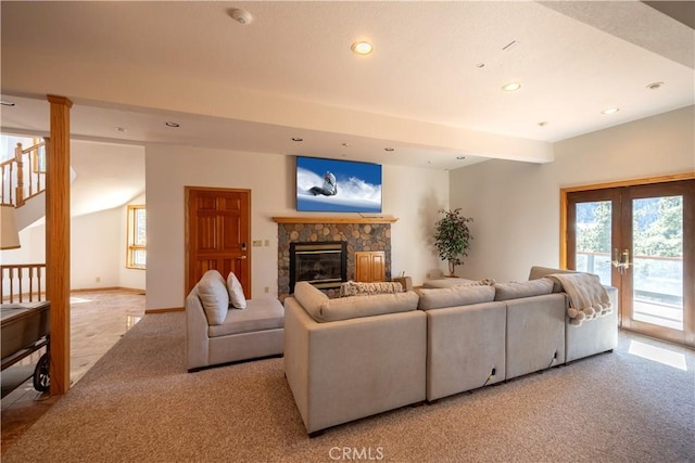 carpeted living room with beam ceiling, french doors, plenty of natural light, and a stone fireplace