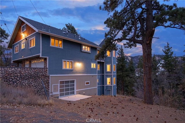 back house at dusk featuring a garage