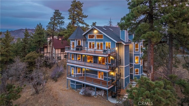 back house at dusk with a mountain view and a balcony