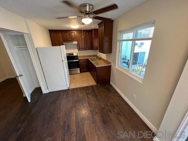 kitchen featuring stainless steel range, white refrigerator, sink, light wood-type flooring, and ceiling fan