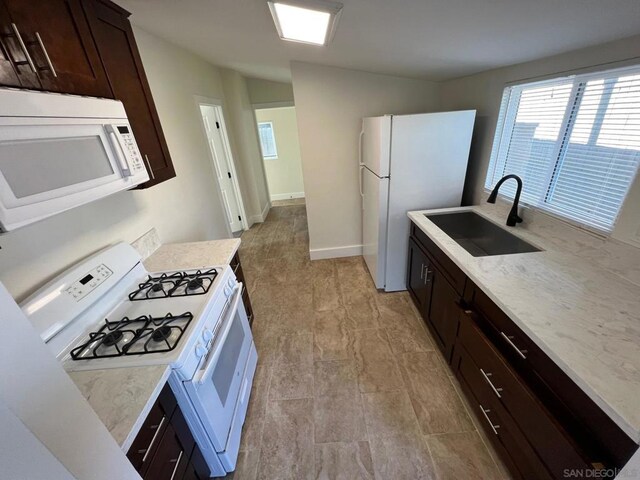 kitchen with sink, white appliances, and dark brown cabinetry