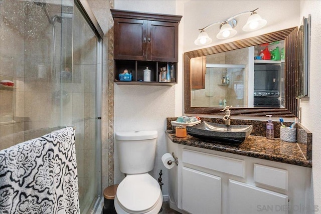 bathroom featuring toilet, a shower with door, and vanity