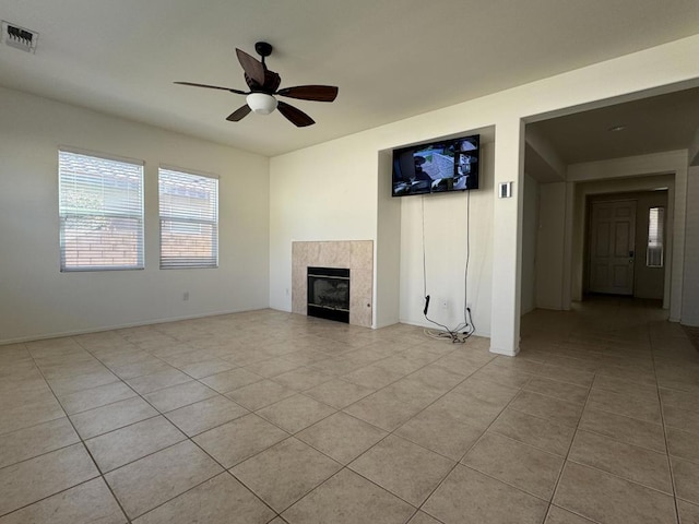 unfurnished living room with ceiling fan, a tiled fireplace, and light tile patterned flooring