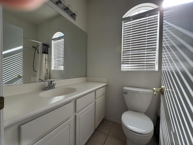 bathroom with toilet, vanity, tile patterned flooring, and walk in shower