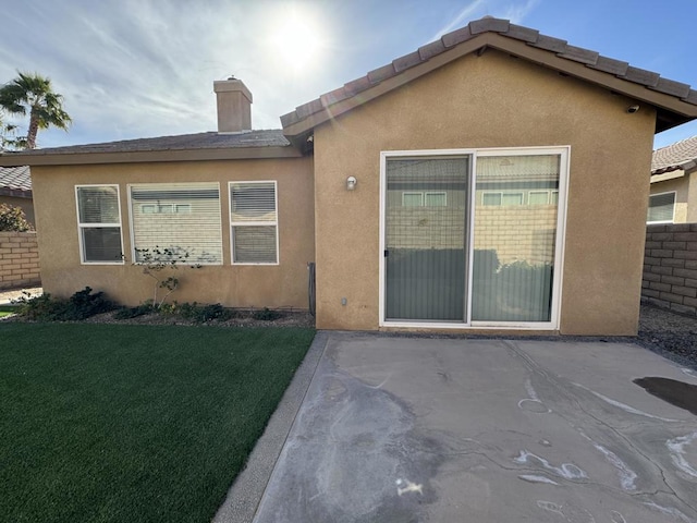 rear view of house featuring a lawn and a patio