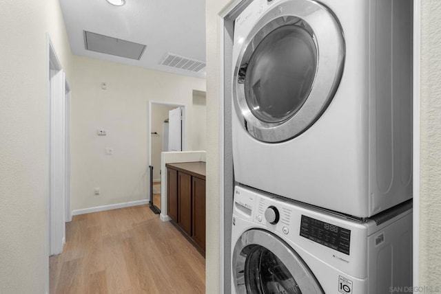 laundry room featuring light wood-type flooring and stacked washer and clothes dryer