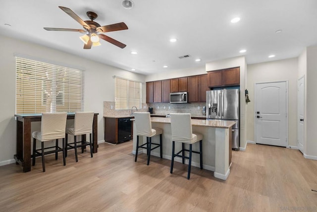 kitchen with a breakfast bar, a center island, stainless steel appliances, and light hardwood / wood-style flooring