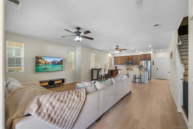 living room with ceiling fan and light hardwood / wood-style flooring