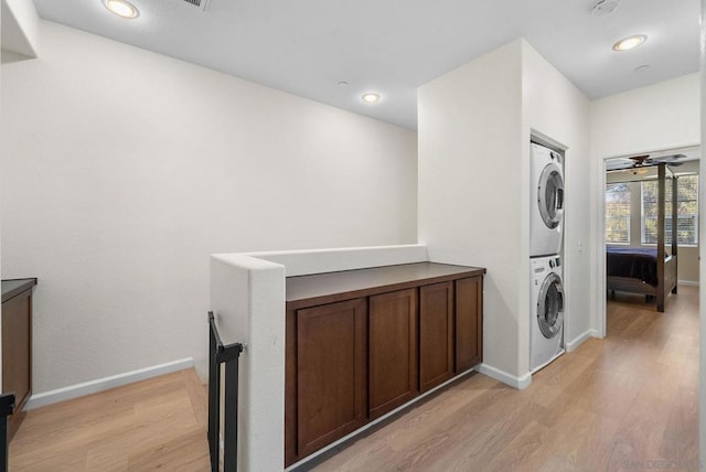 washroom with stacked washer and dryer, ceiling fan, and light wood-type flooring