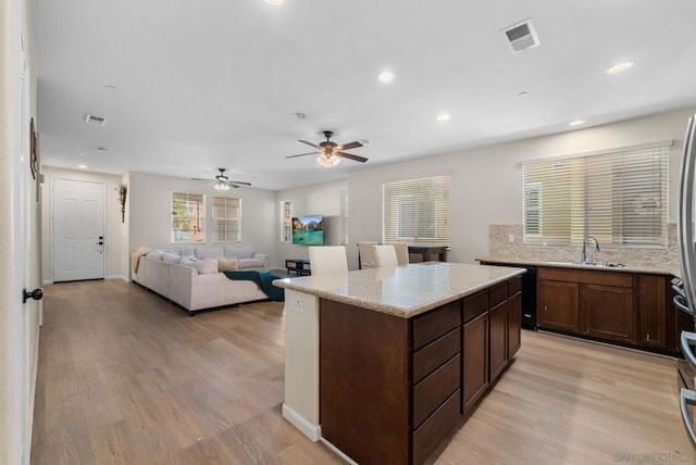 kitchen featuring ceiling fan, light wood-type flooring, sink, and a kitchen island