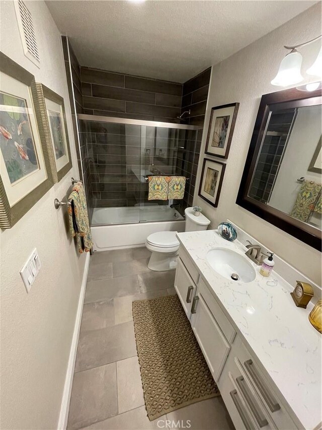 full bathroom featuring a textured ceiling, shower / bath combination with glass door, tile patterned flooring, vanity, and toilet