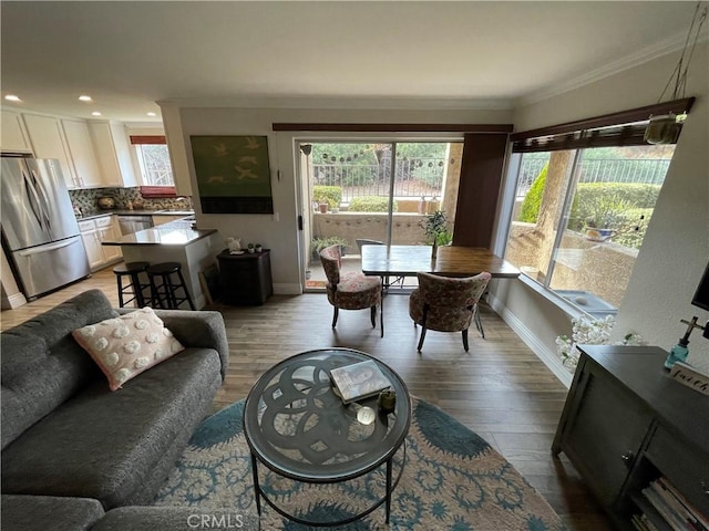 living room with light wood-type flooring, ornamental molding, and plenty of natural light