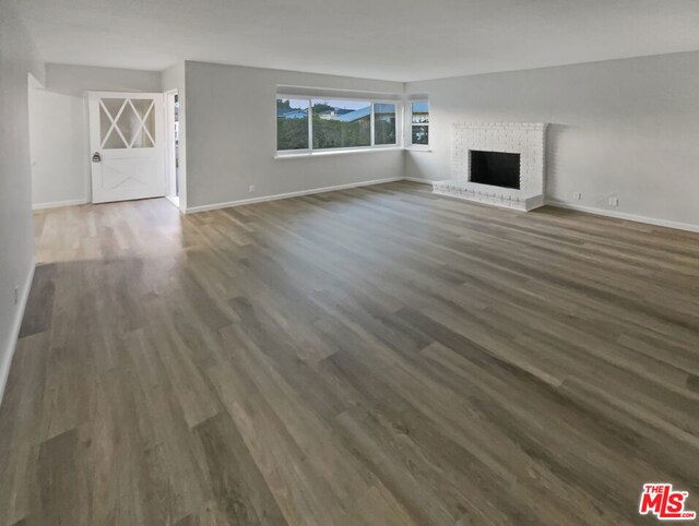 unfurnished living room featuring a fireplace and dark hardwood / wood-style floors