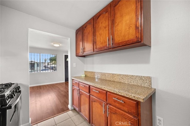 kitchen featuring range with gas cooktop, light tile patterned flooring, and light stone counters