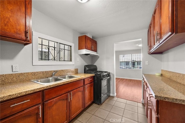 kitchen featuring light stone countertops, light tile patterned floors, black gas stove, and sink